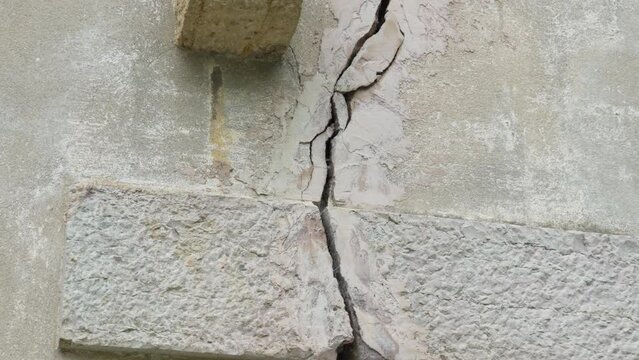 Crack in the foundation of a building from an earthquake close-up. Broken fractured wall of the house. Consequences of natural disasters
