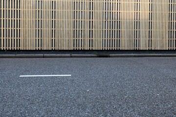 Closeup of a asphalt road with a linear fence pattern