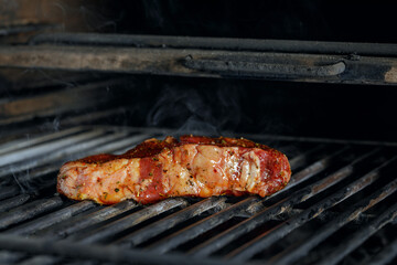  Raw meat beef steak  grilling on rack charcoal stove with smoke on black background.