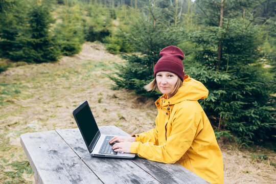 Woman working on laptop outdoors surrounded by beautiful nature