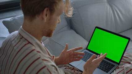 Guy using green laptop computer closeup. Online teacher talking video conference