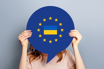 A young woman holds a paper poster with the image of the flag of the European Union and Ukraine