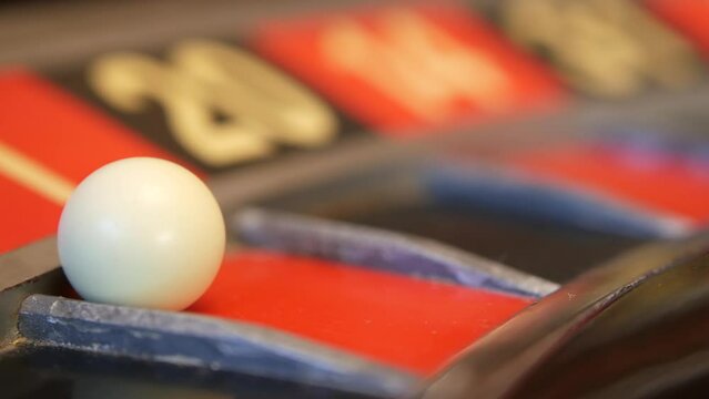 Ball on wooden french roulette table in casino. Wheel spinning, turning or rotating. Odd and even numbers, black, red and zero sectors. Bets in game of chance. Money playing, gambling or risky betting