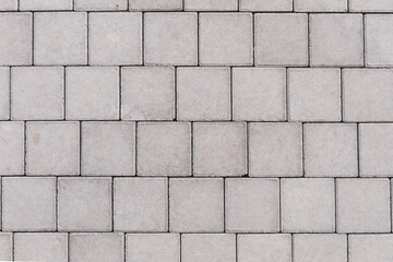 Obraz premium Gray brick stone on street. Top view. pavement texture with concrete bricks