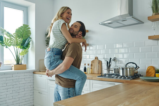 Beautiful young couple embracing and having fun at the domestic kitchen