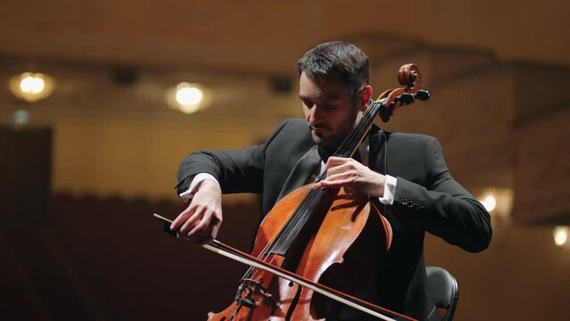 talented cellist is playing cello on scene in concert hall, violoncellist in symphonic orchestra