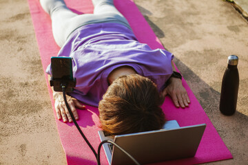 An old slender woman does yoga in the park online
