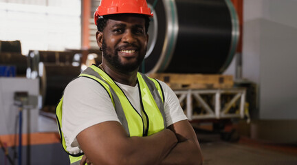 Portrait of happy professional African American male engineer wearing safety helmet standing and...