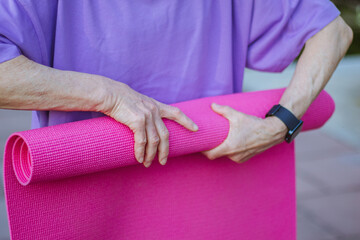 An old slender woman does yoga in the park