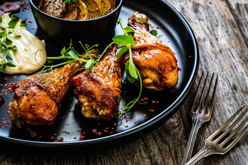 Barbecued chicken drumsticks with fried potato on wooden table
