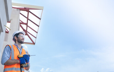 Hispanic man holding cordless drill professional worker.banner cover design male professional builder with construction tools holding a safety white helmet while standing outdoor of construction site.