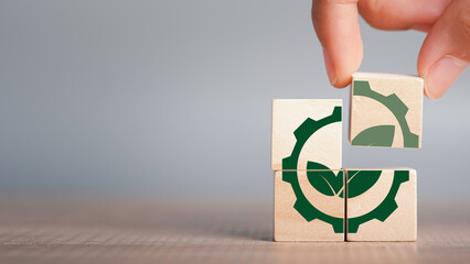 Greenwashing concept. Green leaf and gear icon in wood cube Company investing more time and money...