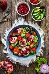 Tasty salad - roast pork loin, cucumber, cherry tomatoes, pomegranate, strawberries and fresh, green vegetables on wooden table
