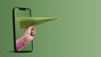 Hand holding a paper plane in a smartphone