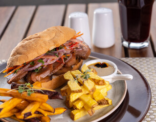 Sandwich de carne en un plato en la mesa de un restaurante.