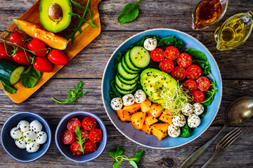 Fresh salad - mozzarella, melon and vegetables on wooden table
