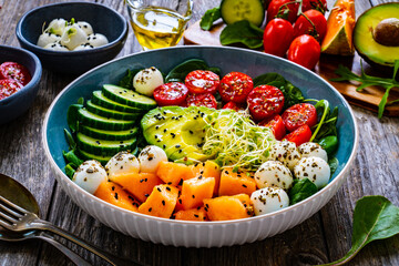 Fresh salad - mozzarella, melon and vegetables on wooden table
