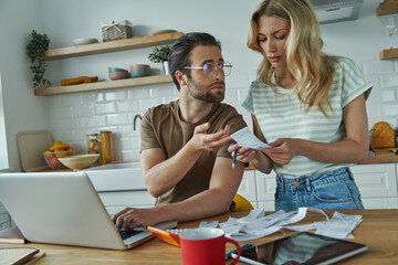 Concentrated young couple calculating finances at the domestic kitchen