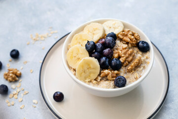 Oatmeal porridge with walnuts, blueberries and bananas - healthy rustic breakfast