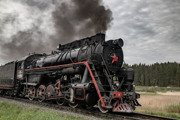 Obraz premium An old steam locomotive Ruskeala Express arriving at Sortavala station. Historical train in Karelia.
