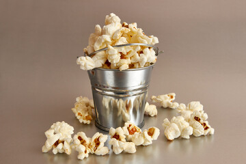 Small bucket filled with popcorn on a gray background.