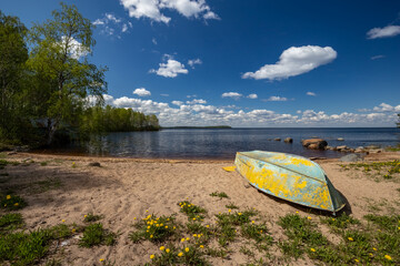 An old boat on the shore of Karelian Lake on a sunny day.