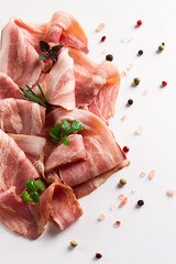 Raw bacon, sliced, with micro greenery and spices, on a white background, close-up,