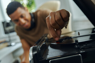 Close-up of cheerful young African man turning on the turntable