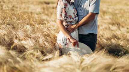 Couple taking hands and walking on golden wheat field over beautiful sunset.