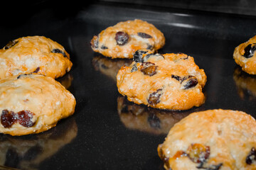 Many baked homemade orange crunchy oatmeal raisin cookies on metal sheet in oven - close up. Dessert, gastronomy, baking and food concept