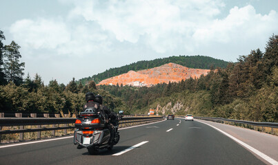 Photo of a modern highway with a beautiful view of the mountains in the background. Couple on a motorcycle riding on the track. European tourist route