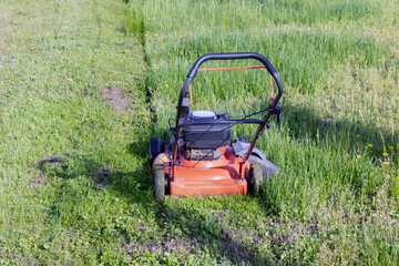 Obraz premium Lawn mower on the grass in a country yard. General form.