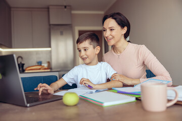 Portrait of cheerful smiled mother and happy little son learning at laptop and smiling.