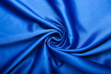 blue silk forming elegant waves with shadows and chiaroscuro, background of textile material
