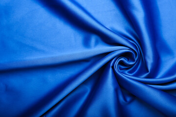 blue silk forming elegant waves with shadows and chiaroscuro, background of textile material
