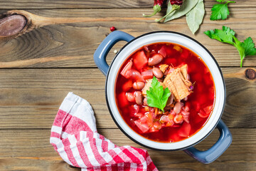 Bean beef beetroot soup borscht in pot on dark wooden background. Top view, copy space.