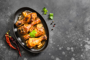 Drumsticks air fryer chicken legs in cast iron skillet on dark background. Top view, copy space.
