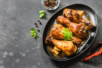 Oven baked soy sauce chicken legs in cast iron skillet on dark background. Top view, copy space.