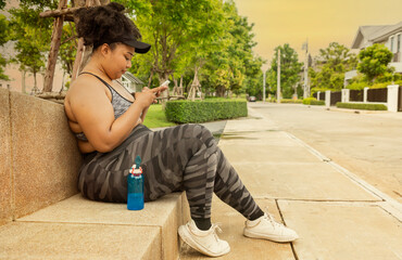 Oversized fat woman exercising, running in the park, sitting and resting, holding a smartphone,...