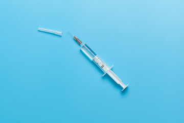 Medical syringe for liquid 5 ml. White medical syringe with a cap, isolated on a blue background. - 513376672