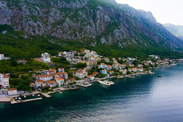 Fototapeta na wymiar Montenegro. Adriatic Sea. Bay of Kotor. Popular tourist spot. Village on the coast. Houses with orange tiled roofs. Summer. Tourist season. Drone. Aerial view