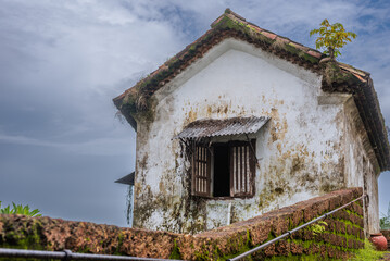Fototapeta na wymiar Interiors of a fort in Goa which shows the building architecture of Portuguese colonial influence having laterite stones, windows, doors and tiled roofs with the Monsoon sky in background
