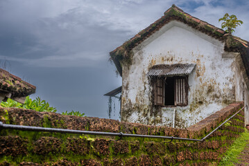 Fototapeta na wymiar Interiors of a fort in Goa which shows the building architecture of Portuguese colonial influence having laterite stones, windows, doors and tiled roofs with the Monsoon sky in background