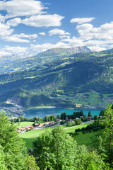 Panoramic view of lake, countryside, green alpine meadows and mountains