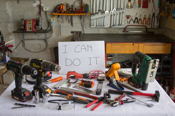 Picture of a table with various work tools and a sign saying "I can fix it"