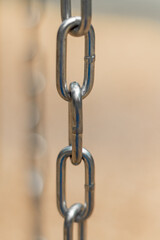 Vertical, partial blurred iron chain on blurred background. Low angle view of steel chains.