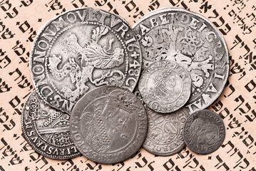 Heap of old silver coins on open Siddur page. Selective focus. Closeup.