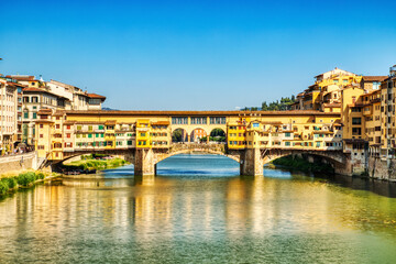 Fototapeta na wymiar Ponte Vecchio Bridge during Beautiful Sunny Day with Reflection in Arno River, Florence
