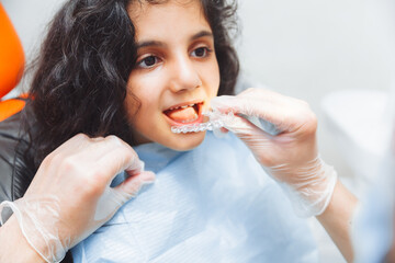 teen girl holding braces, dentist puts braces on girl. dental care and orthodontic concept.