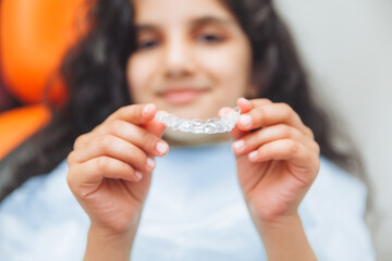 teen girl holding braces, dentist puts braces on girl. dental care and orthodontic concept.